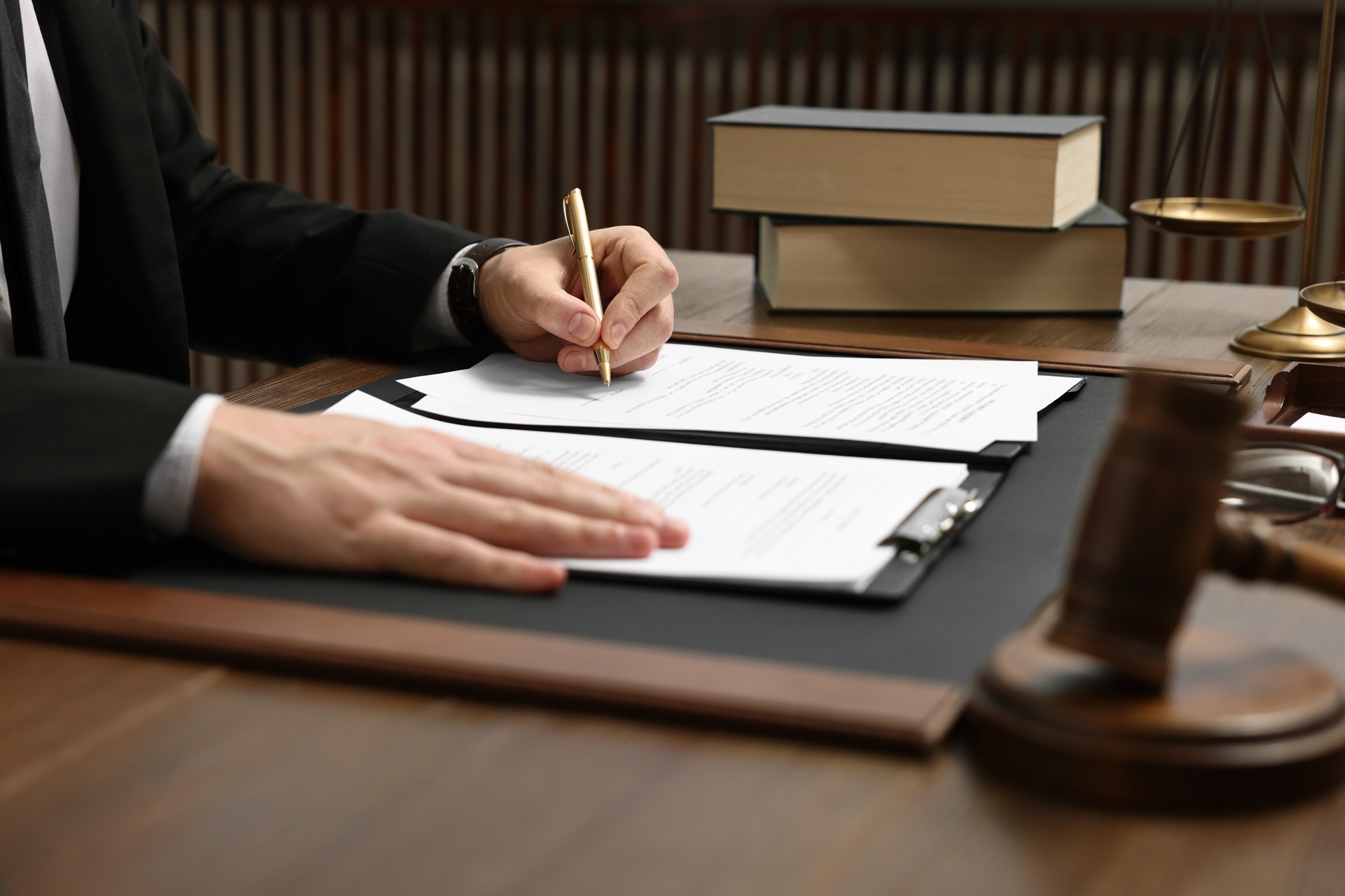 Lawyer working with documents at wooden table indoors, closeup